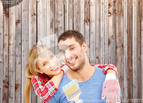 Image of smiling couple covered with paint with paint brush