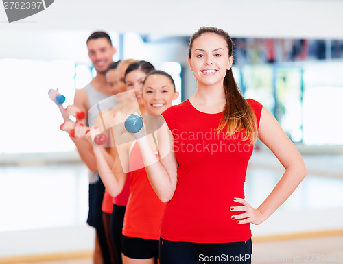 Image of group of smiling people with dumbbells in the gym