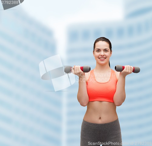 Image of young sporty woman with light dumbbells