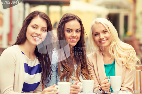 Image of three beautiful girls drinking coffee in cafe