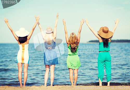 Image of girls looking at the sea with hands up
