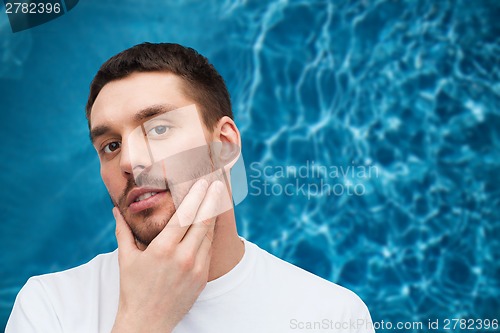 Image of beautiful calm man touching his face