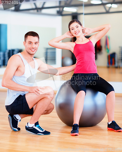 Image of male trainer with woman doing crunches on the ball