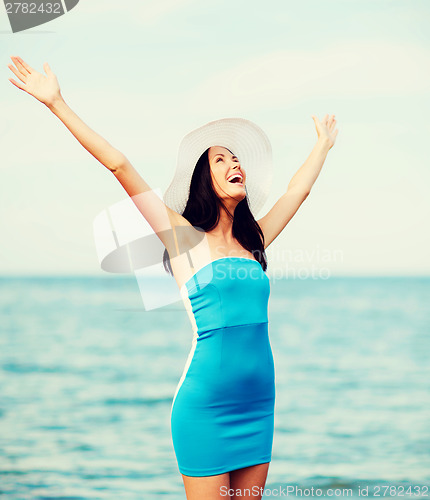Image of girl with hands up on the beach
