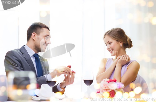 Image of man proposing to his girlfriend at restaurant