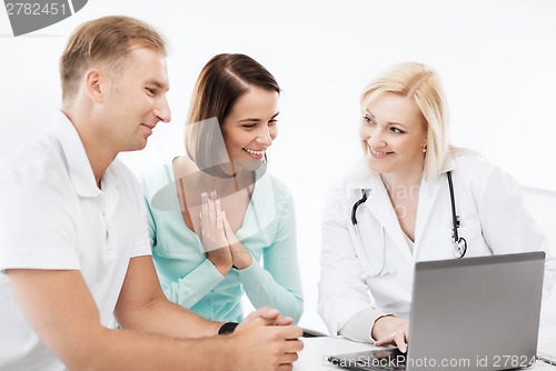 Image of doctor with patients looking at laptop