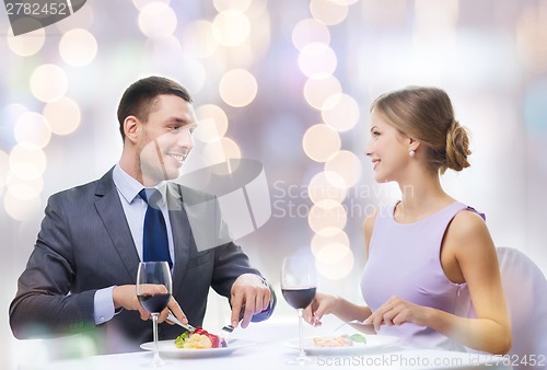 Image of smiling couple eating main course at restaurant