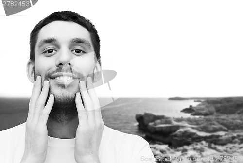 Image of beautiful smiling man touching his face