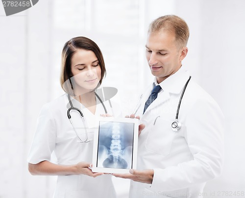 Image of two doctors showing x-ray on tablet pc