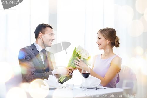 Image of smiling man giving flower bouquet at restaurant