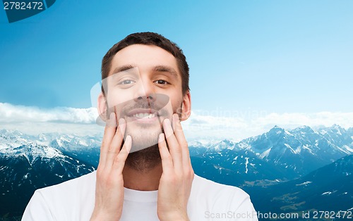 Image of beautiful smiling man touching his face