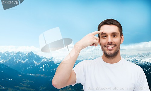 Image of smiling young handsome man pointing to forehead