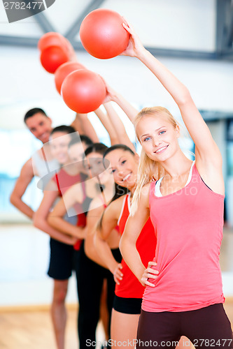 Image of group of smiling people working out with ball