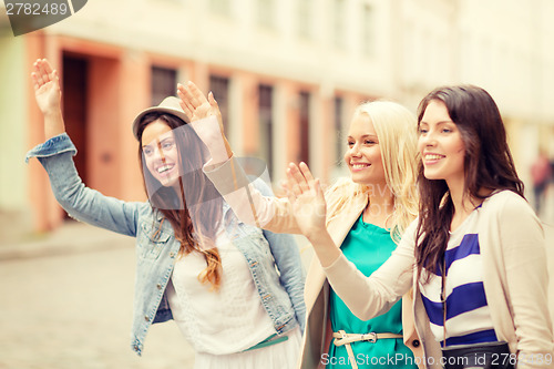 Image of three beautiful girls waving hands