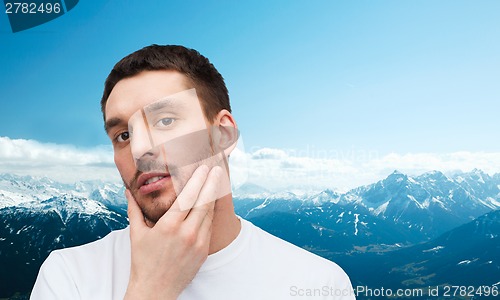 Image of beautiful calm man touching his face