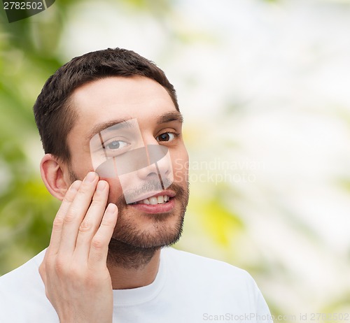 Image of beautiful smiling man touching his face