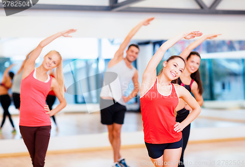 Image of group of smiling people stretching in the gym
