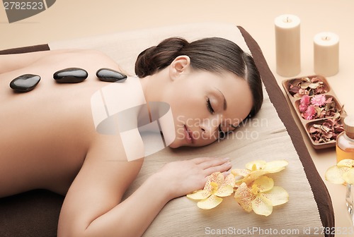 Image of asian woman in spa with hot stones