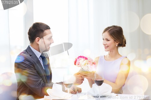 Image of smiling man giving flower bouquet at restaurant