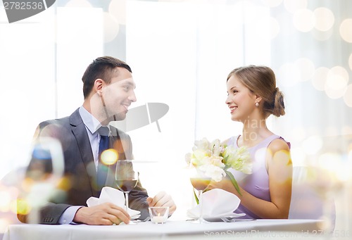 Image of smiling man giving flower bouquet at restaurant