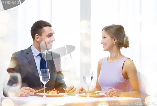 Image of smiling couple eating main course at restaurant