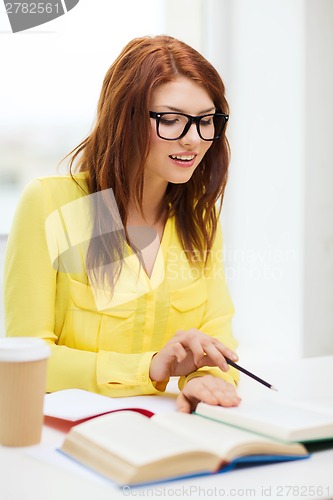 Image of smiling student girl reading books in library