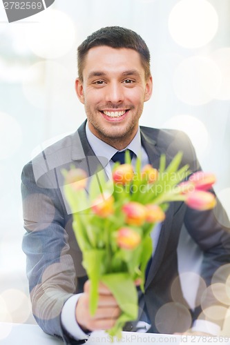Image of smiling handsome man giving bouquet of flowers