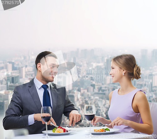 Image of smiling couple eating main course at restaurant