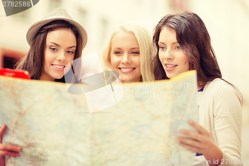 Image of beautiful girls looking into tourist map in city