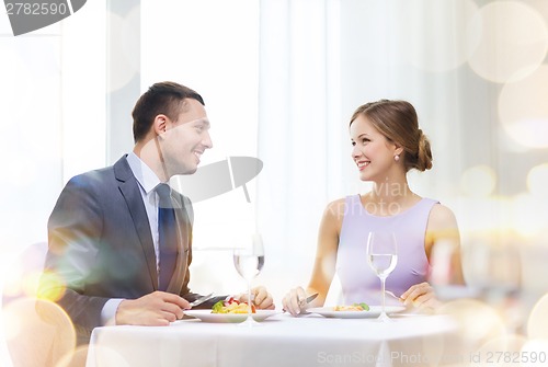 Image of smiling couple eating main course at restaurant