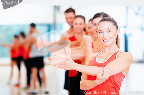 Image of group of smiling people stretching in the gym