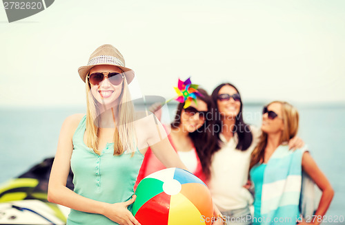 Image of girl with ball and friends on the beach