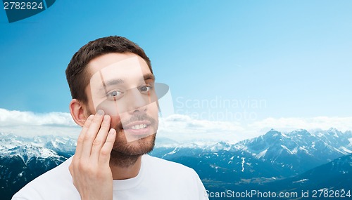 Image of beautiful smiling man touching his face