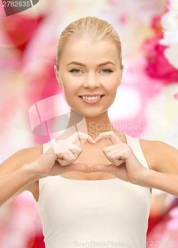 Image of smiling young woman showing heart shape gesture