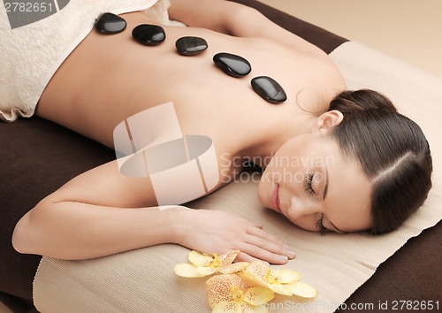 Image of asian woman in spa with hot stones