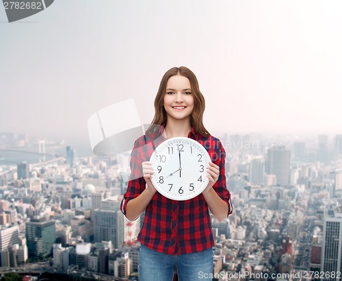 Image of young woman in casual clothes with wall clock