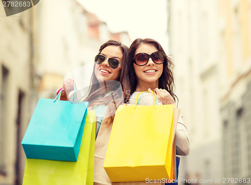 Image of two girls in sunglasses with shopping bags in ctiy