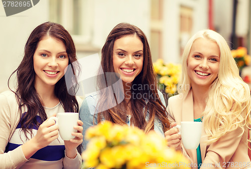 Image of three beautiful girls drinking coffee in cafe