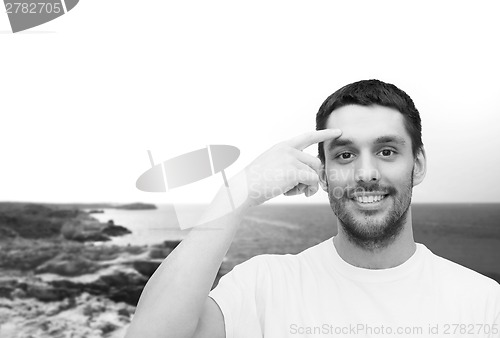 Image of smiling young handsome man pointing to forehead