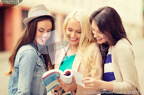 Image of beautiful girls looking into tourist book in city