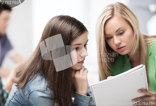 Image of student girls looking at notebook at school