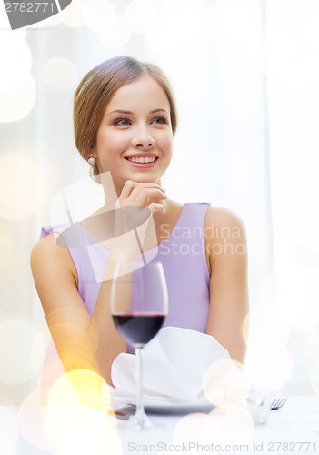 Image of smiling woman with glass of whine waiting for date