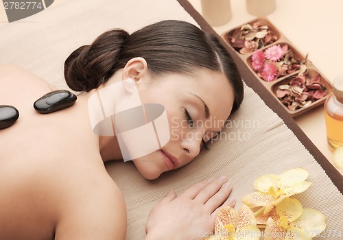 Image of asian woman in spa with hot stones