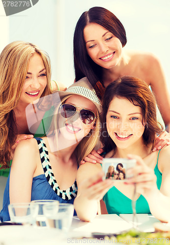 Image of girls taking photo in cafe on the beach