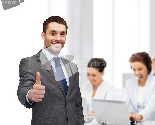 Image of handsome buisnessman showing thumbs up in office