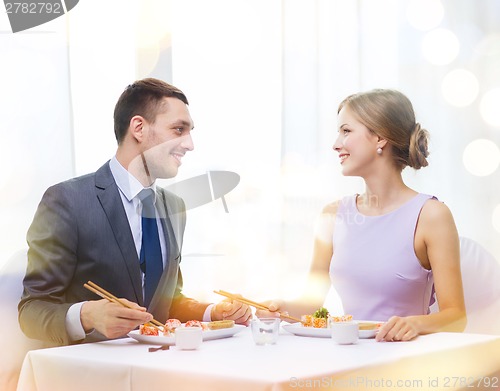 Image of smiling couple eating sushi at restaurant