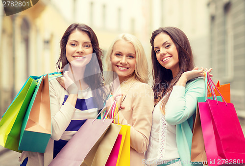 Image of three smiling girls with shopping bags in ctiy