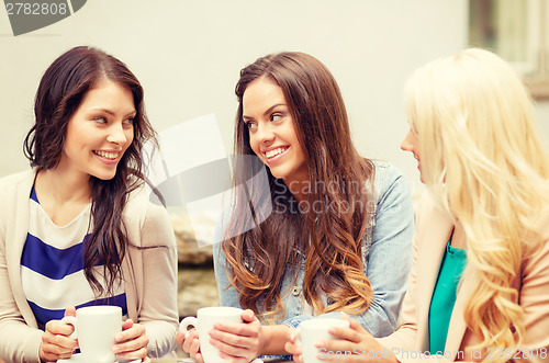 Image of three beautiful girls drinking coffee in cafe