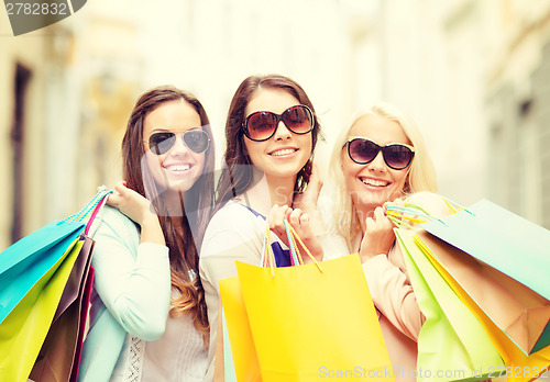 Image of three smiling girls with shopping bags in city