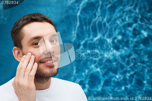 Image of beautiful smiling man touching his face